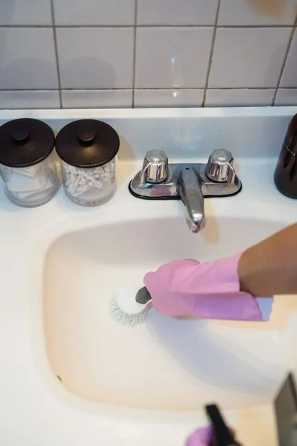 Giovane uomo impegnato nelle pulizie domestiche, mentre pulisce i pannelli di vetro con uno spray bottle.